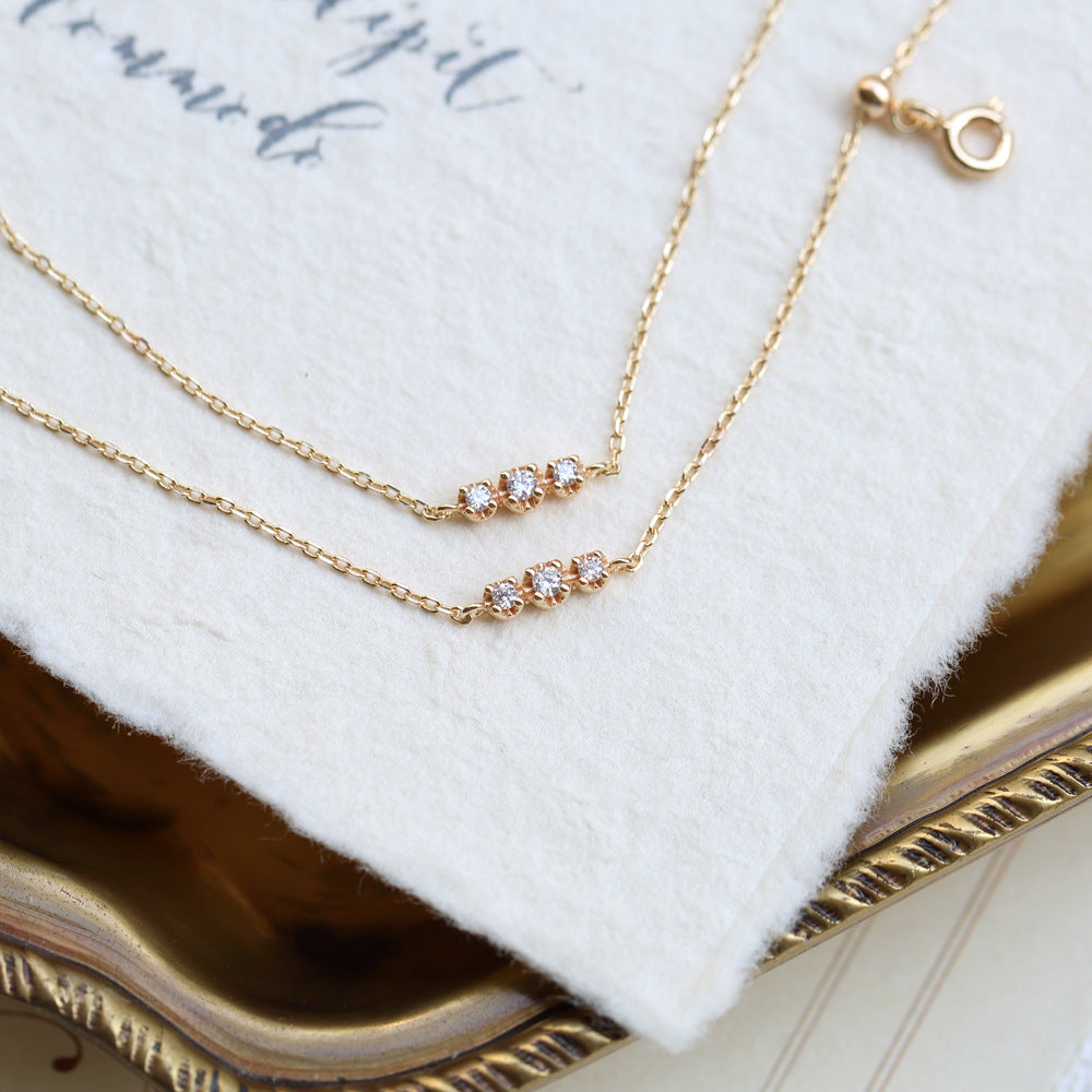 Gold necklace with small diamonds on a white fabric background from The GemBee Jewellery