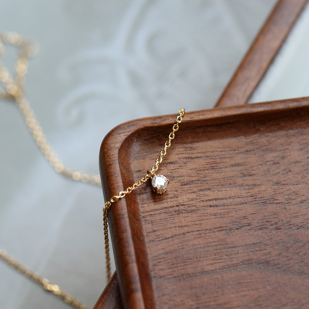 Gold necklace with a diamond pendant on a wooden surface