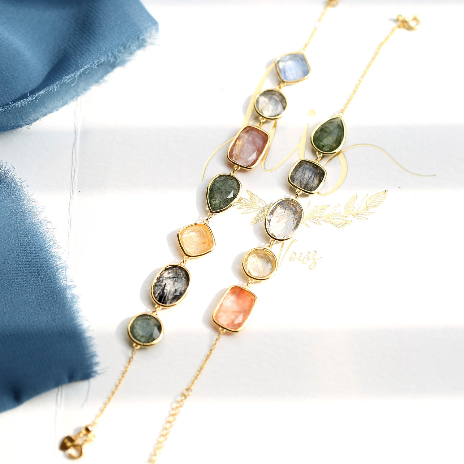 Jewelry set with multicolored stones and gold chains on a white background