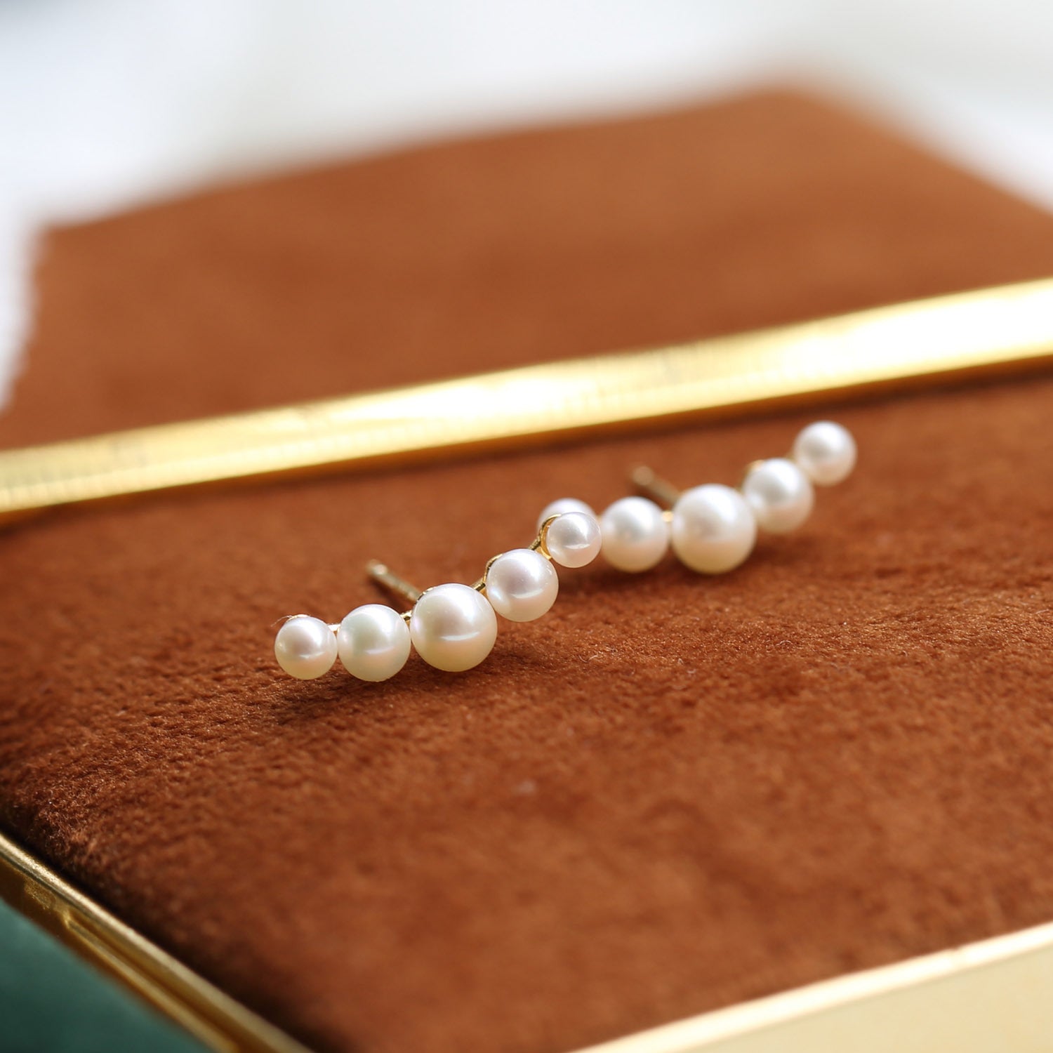 Pearl hairpin on a brown textured surface with a gold hair straightener in the background from Gembee Jewellery