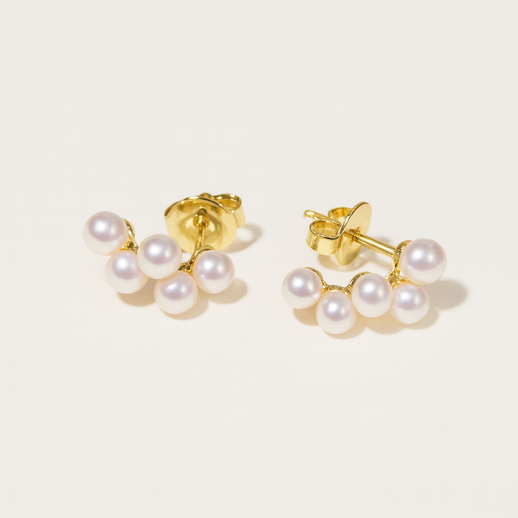 Pair of pearl earrings with gold posts on a light beige background