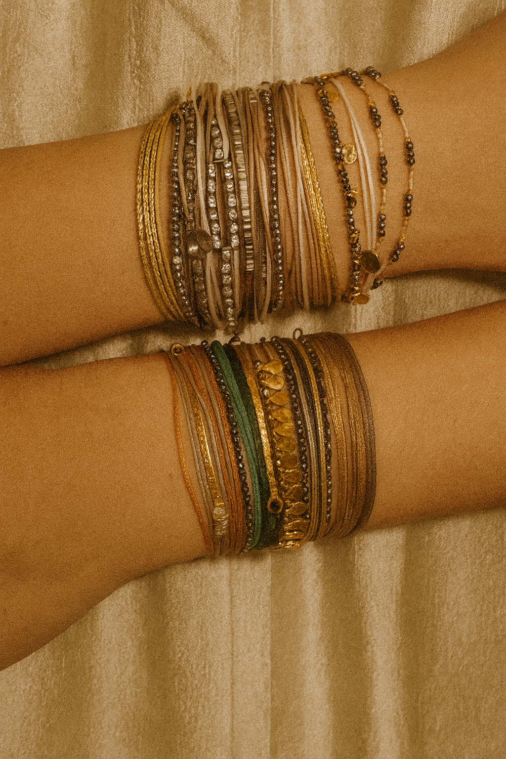 Layered handmade gemstone bracelets with semi-precious stones in warm golden and green tones, photographed in natural light on a neutral background.