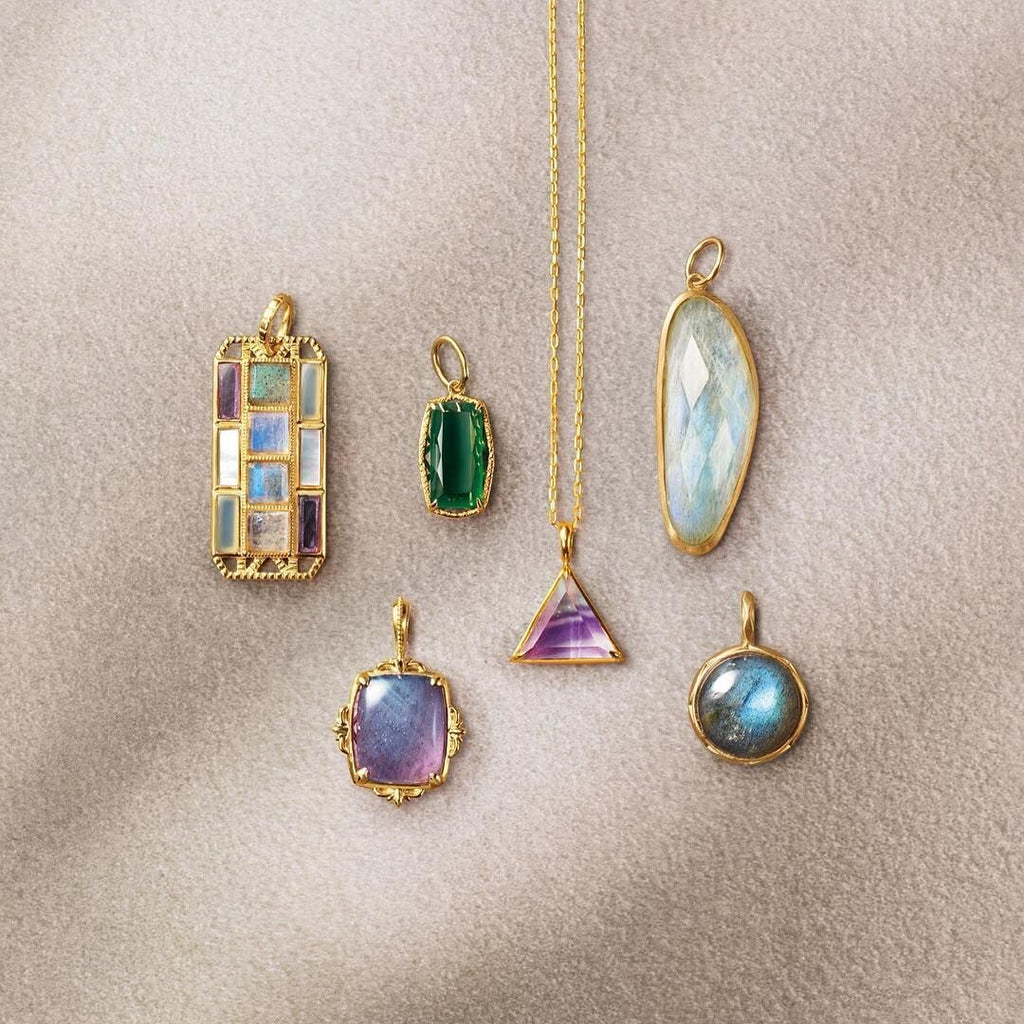 Collection of various gemstone pendants on a beige background