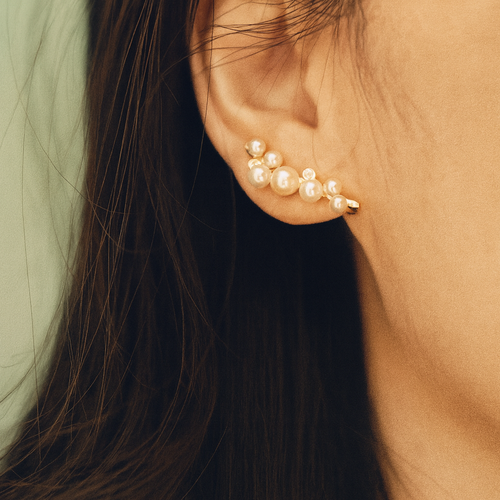 Pearl earring worn by a person with long dark hair.