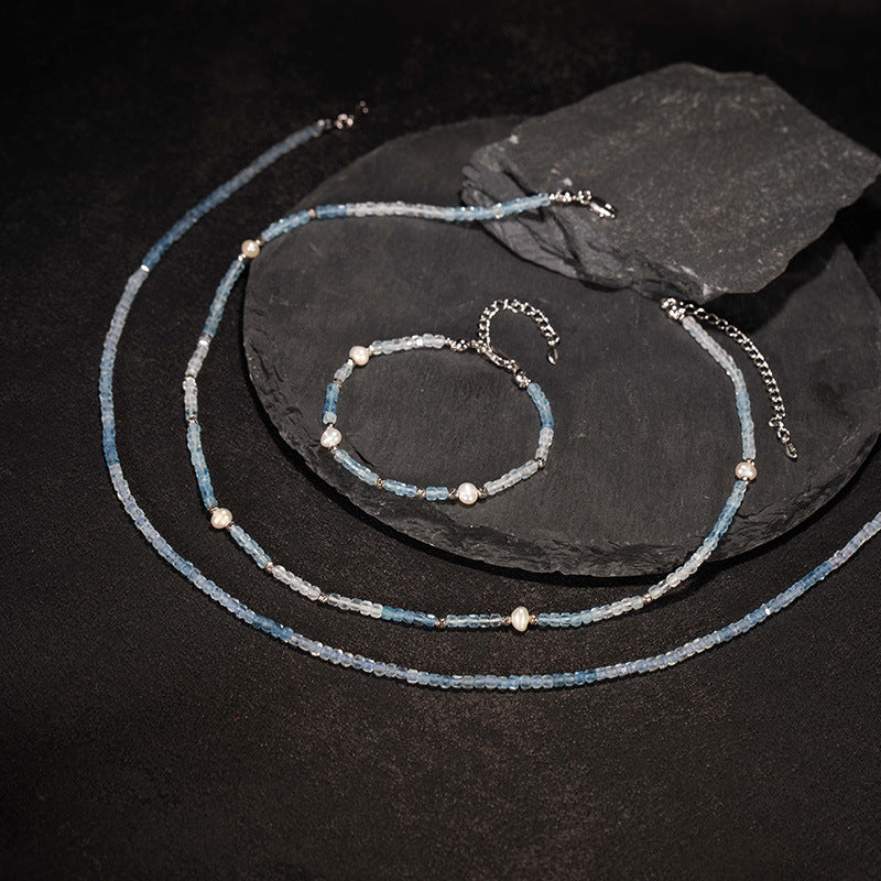 Beaded necklace and bracelet set on a dark surface with a slate stone