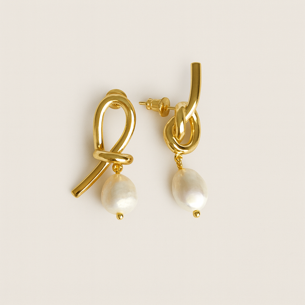 Gold earrings with pearl drops on a light beige background