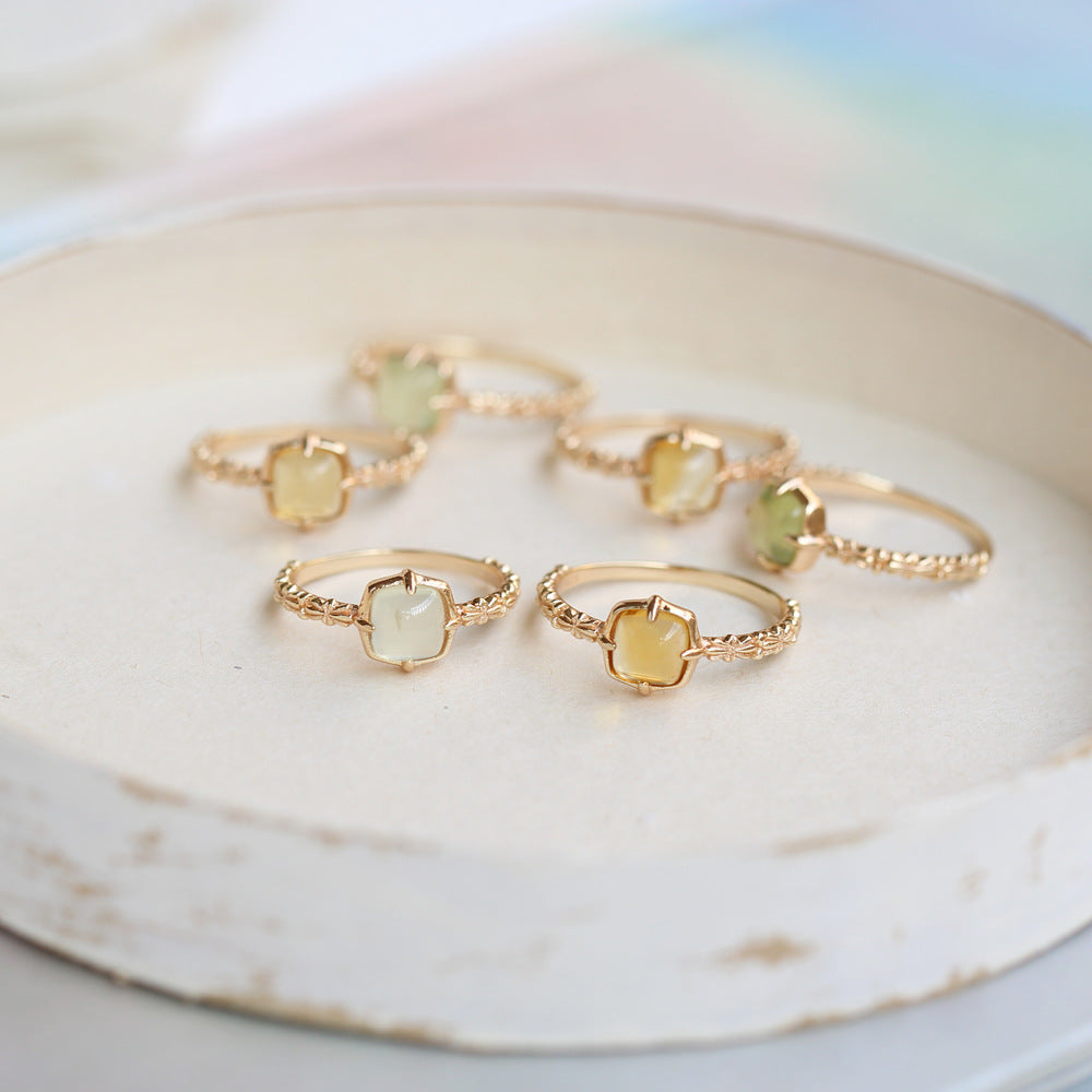 Gold rings with gemstones on a marble surface