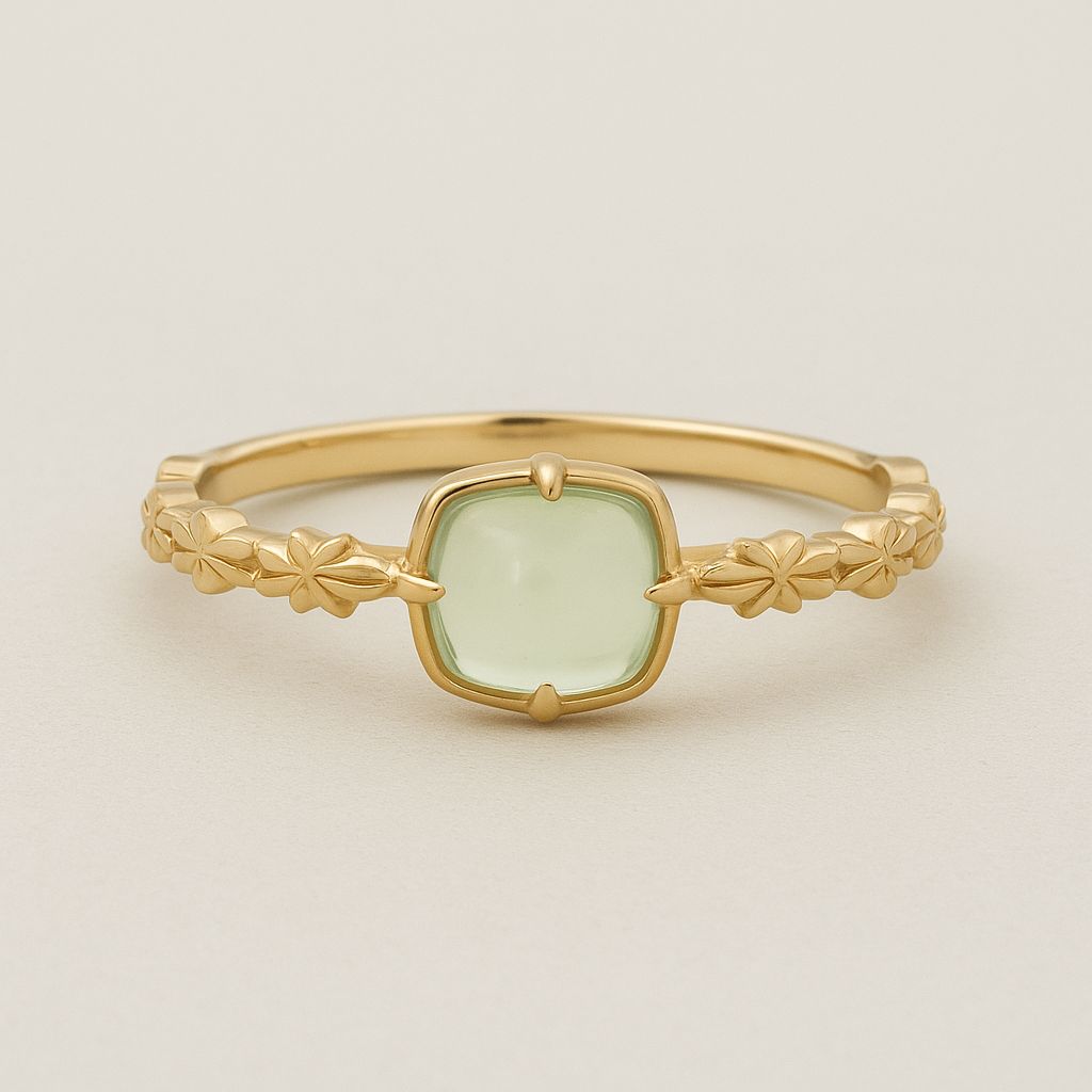 Gold ring with a light green gemstone on a beige background