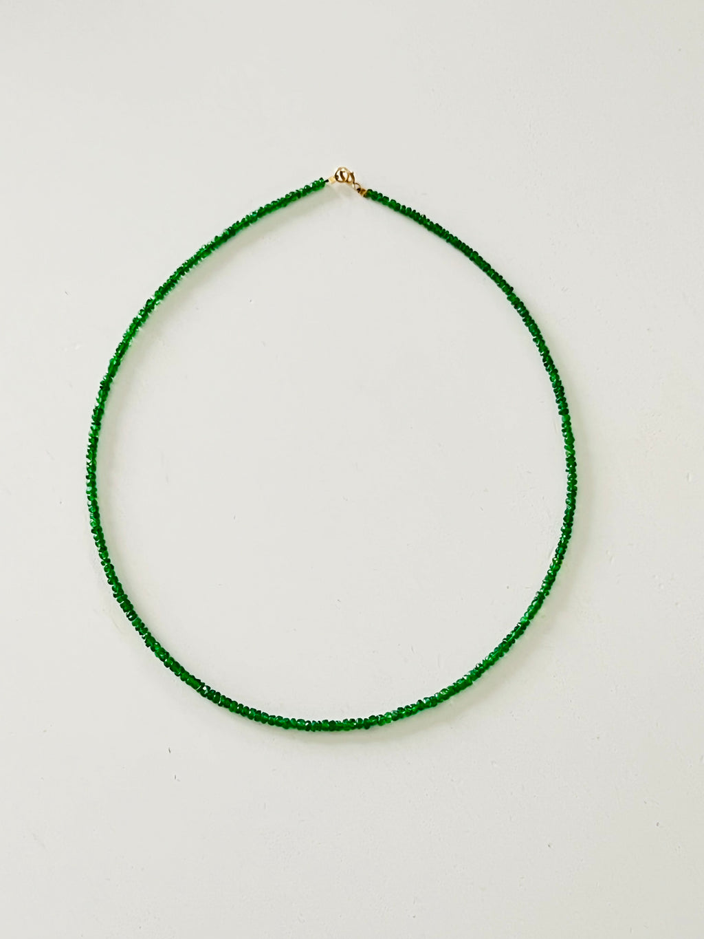 Green beaded necklace on a light gray background