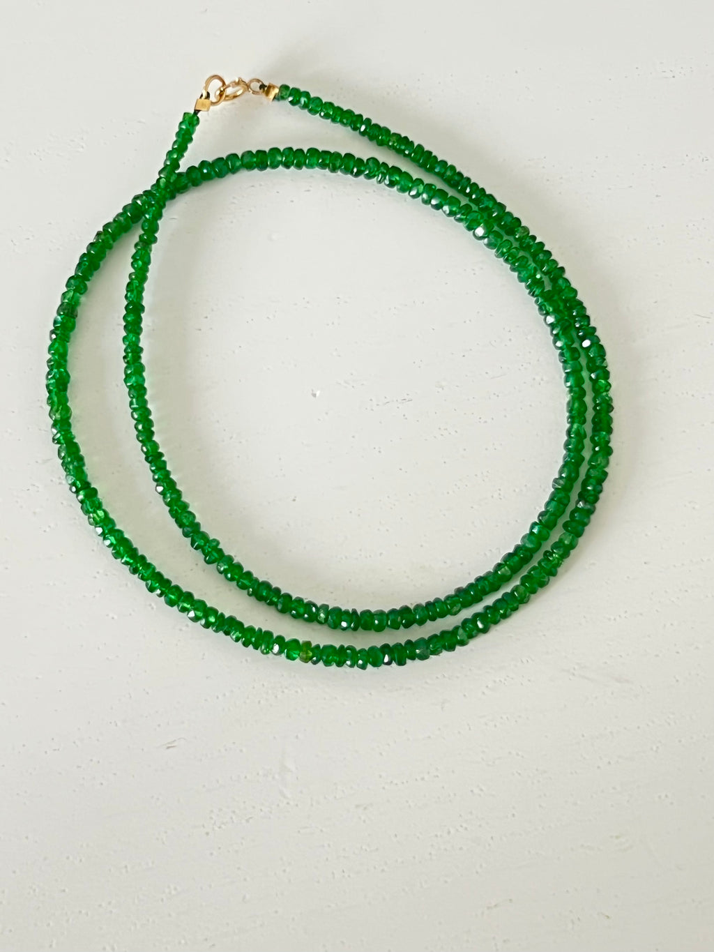 Green beaded necklace on a light gray background