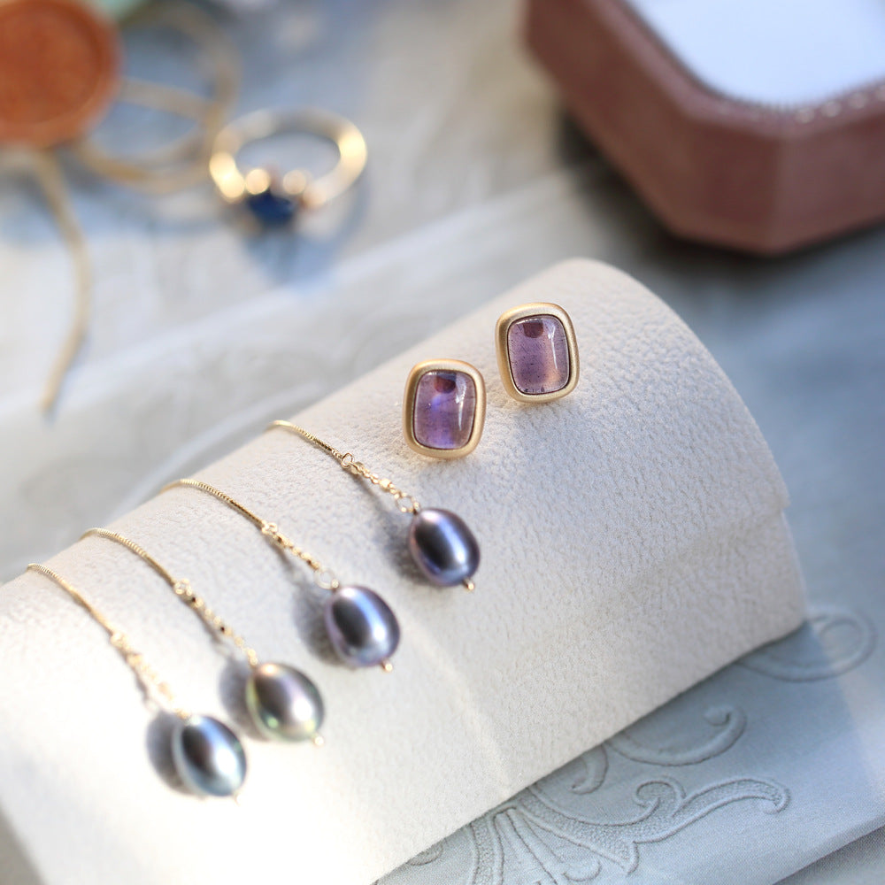 Jewelry set including earrings and necklaces on a white jewelry display.