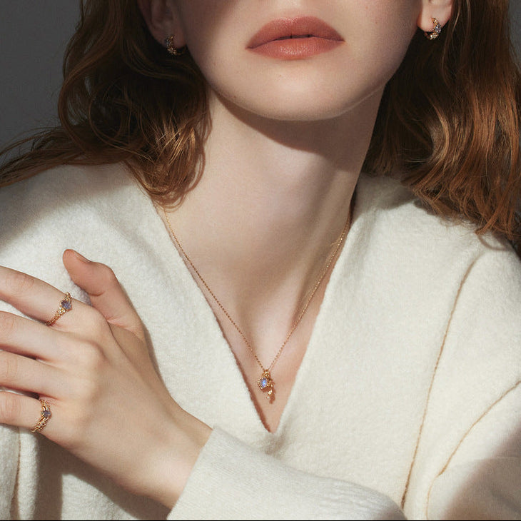 Woman wearing a white sweater with jewelry on a dark background