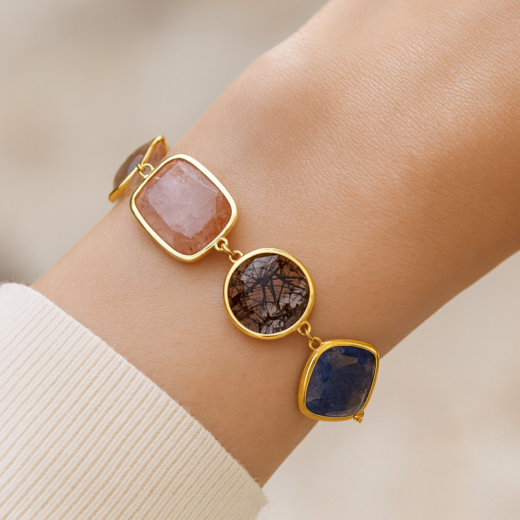 Bracelet with gold accents and stone beads on a wrist against a neutral background