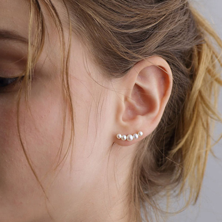 Close-up of an ear wearing pearl stud earrings with a blurred background from Gembee Jewellery 
