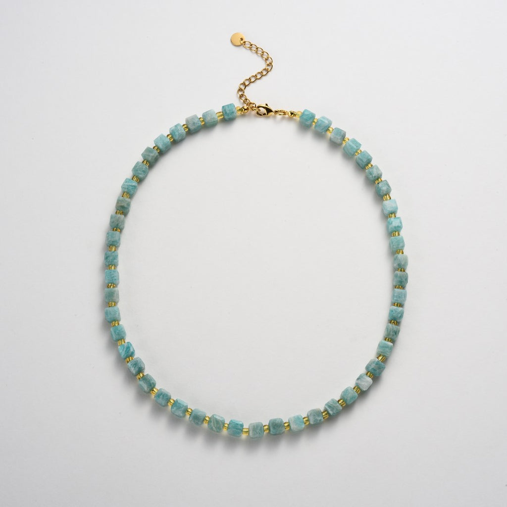 Necklace with blue beads and gold accents on a light gray background