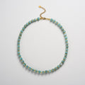 Necklace with blue beads and gold accents on a light gray background