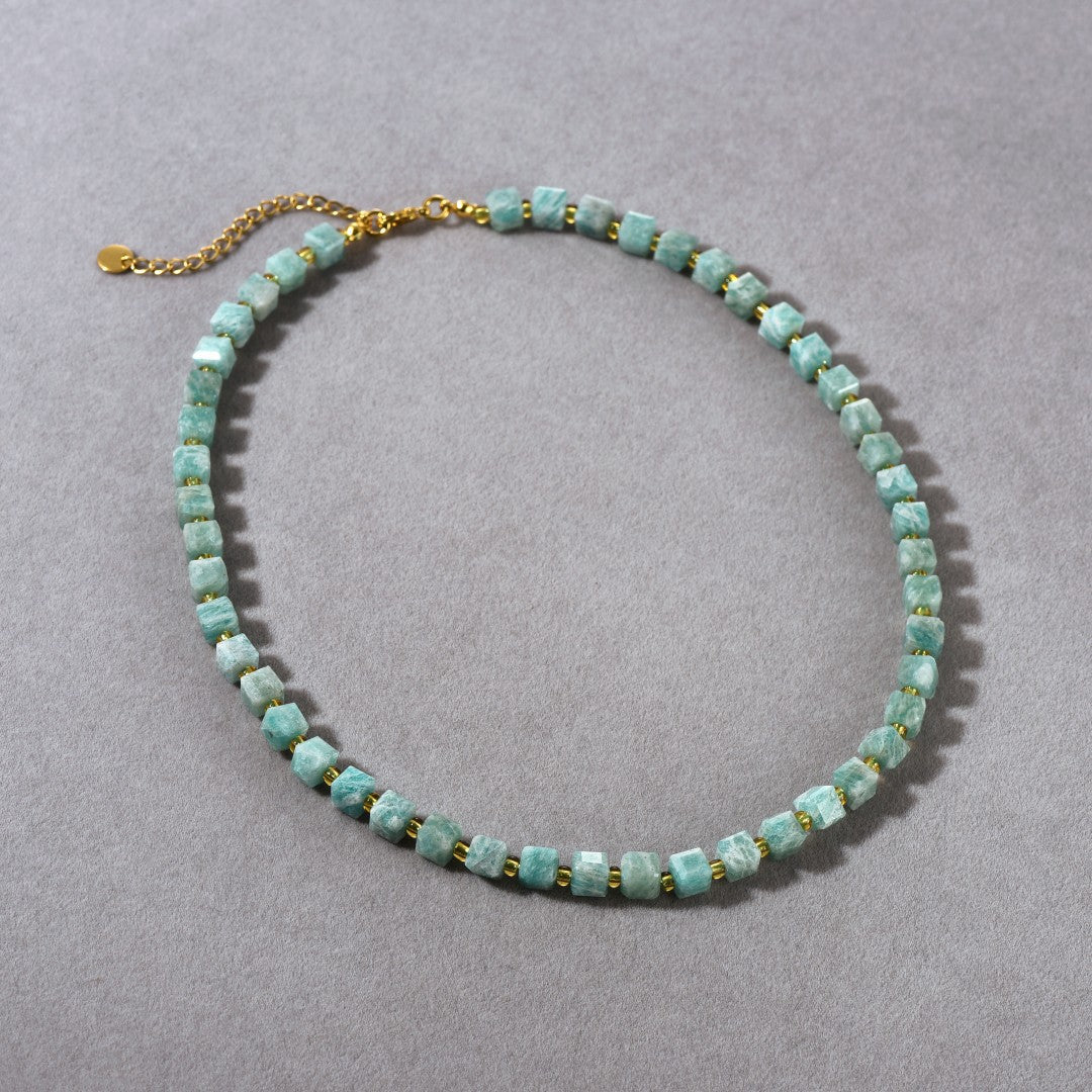 Necklace with turquoise beads and gold chain on a gray background