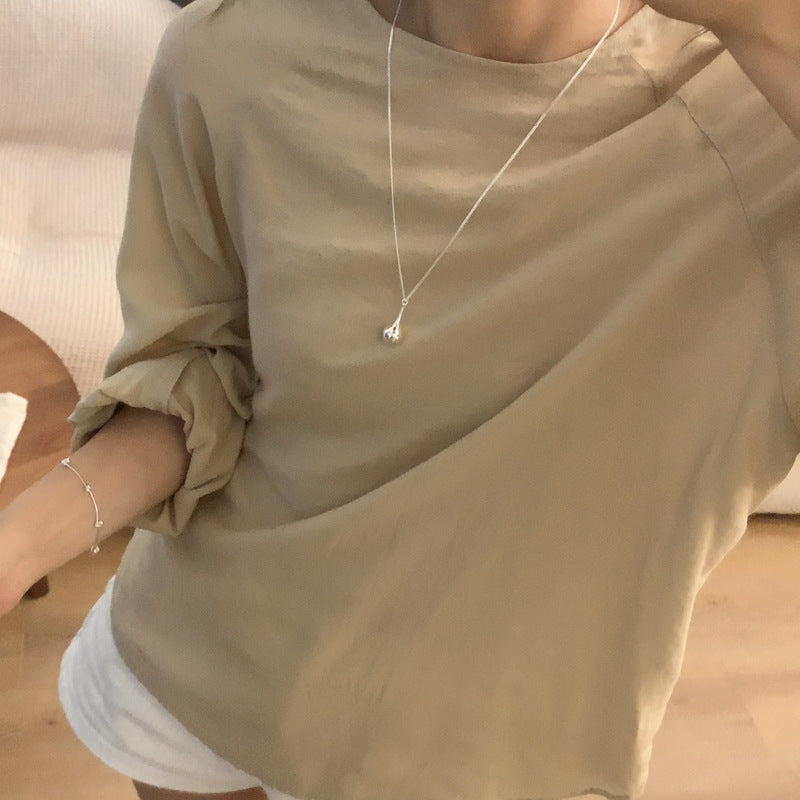 Person wearing a beige shirt and white shorts with a necklace from Gembee Jewellery