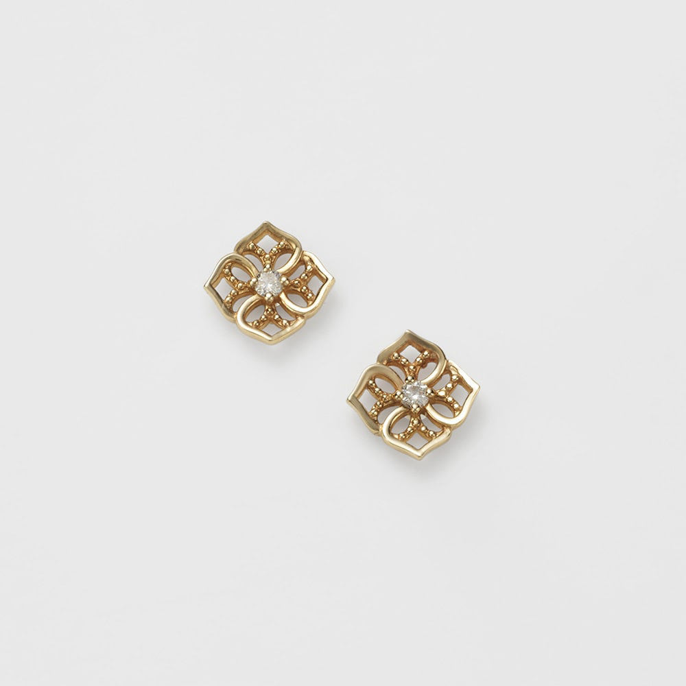 Pair of gold earrings with diamond centers on a light gray background