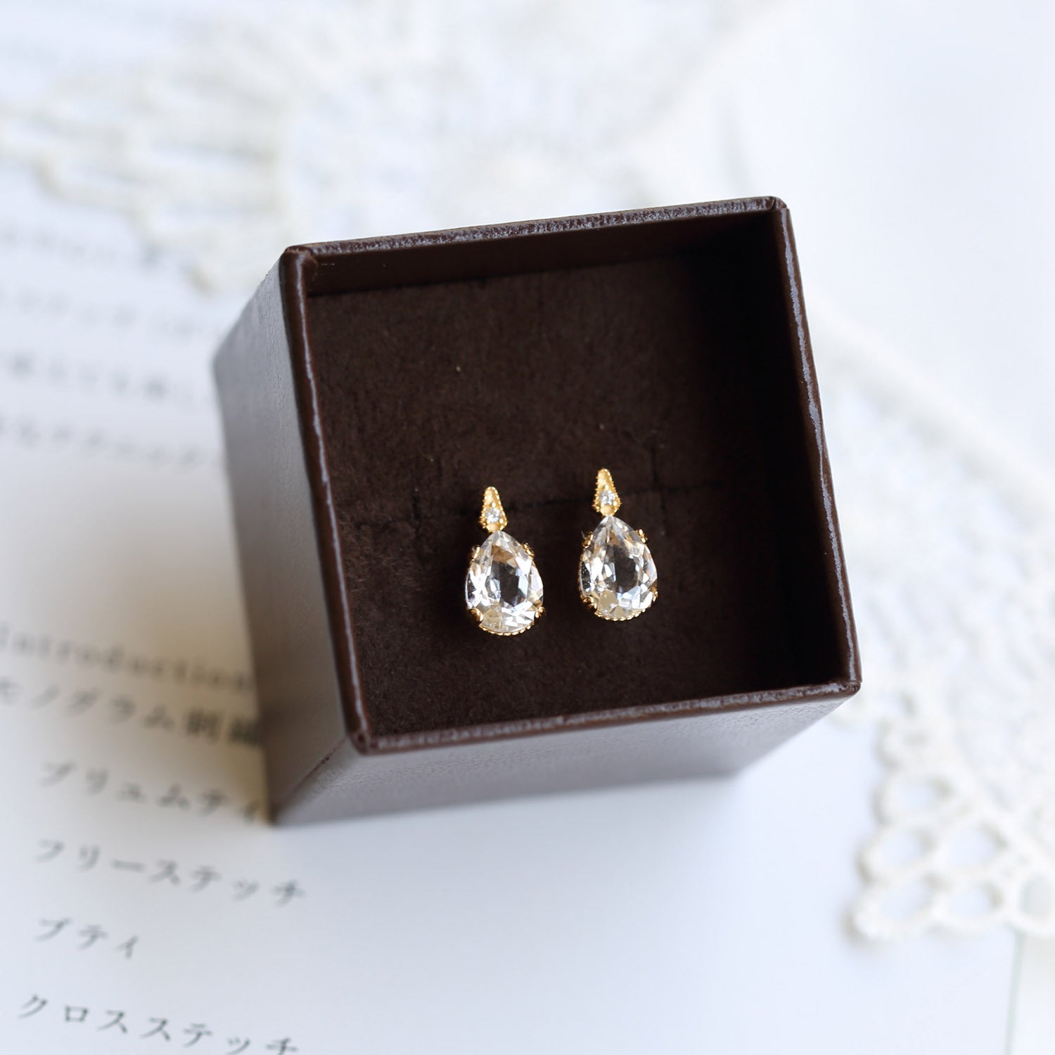 Teardrop-shaped earrings in a brown jewelry box on a light background from the Gembee Jewellery.