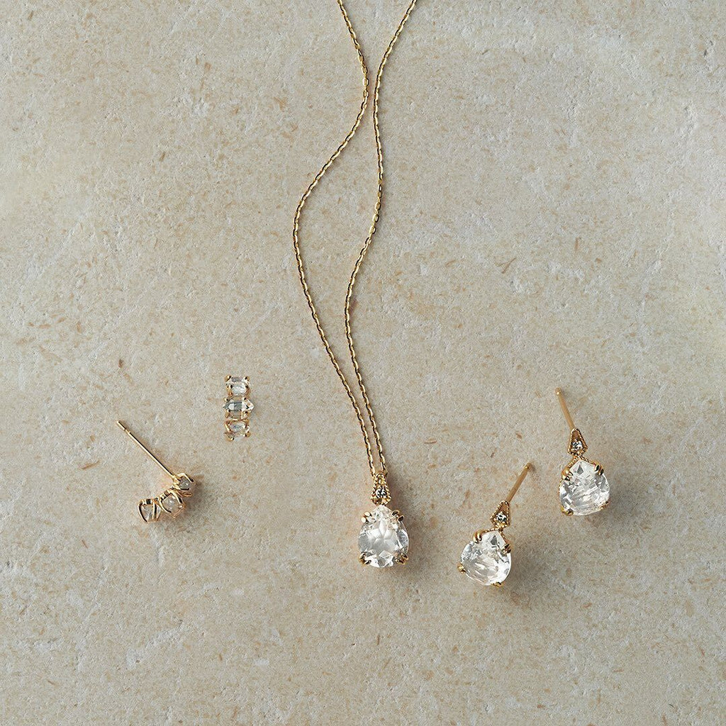 Gold jewelry set with necklace, ring, and earrings on a beige surface from the Gembee Jewellery.
