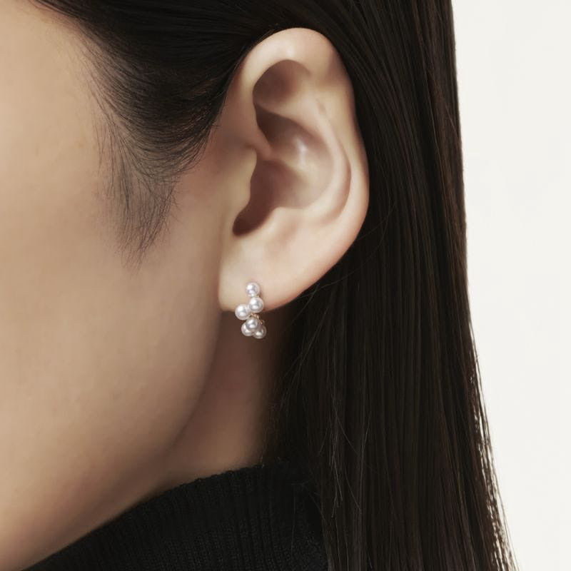 Close-up of an ear wearing pearl earrings with a neutral background